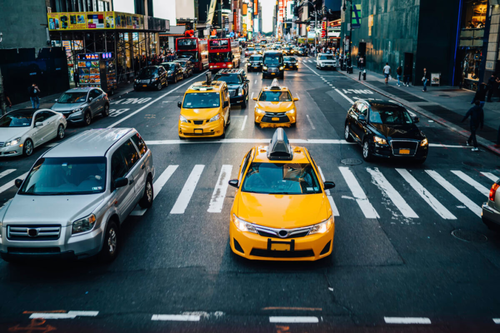 Cars, including three NYC yellow taxis, driving on a one-way street