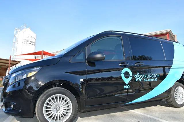 A black minivan with a blue text on the side reading "Via" and "Arlington ON-Demand"
