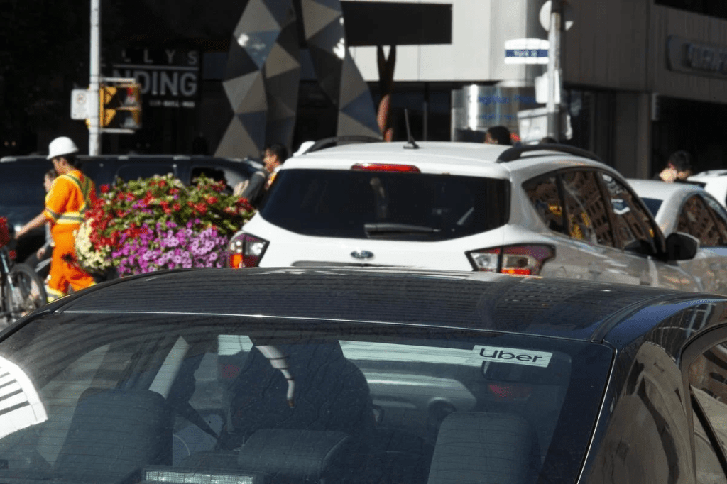 Crowded Toronto street, a car with an Uber sign