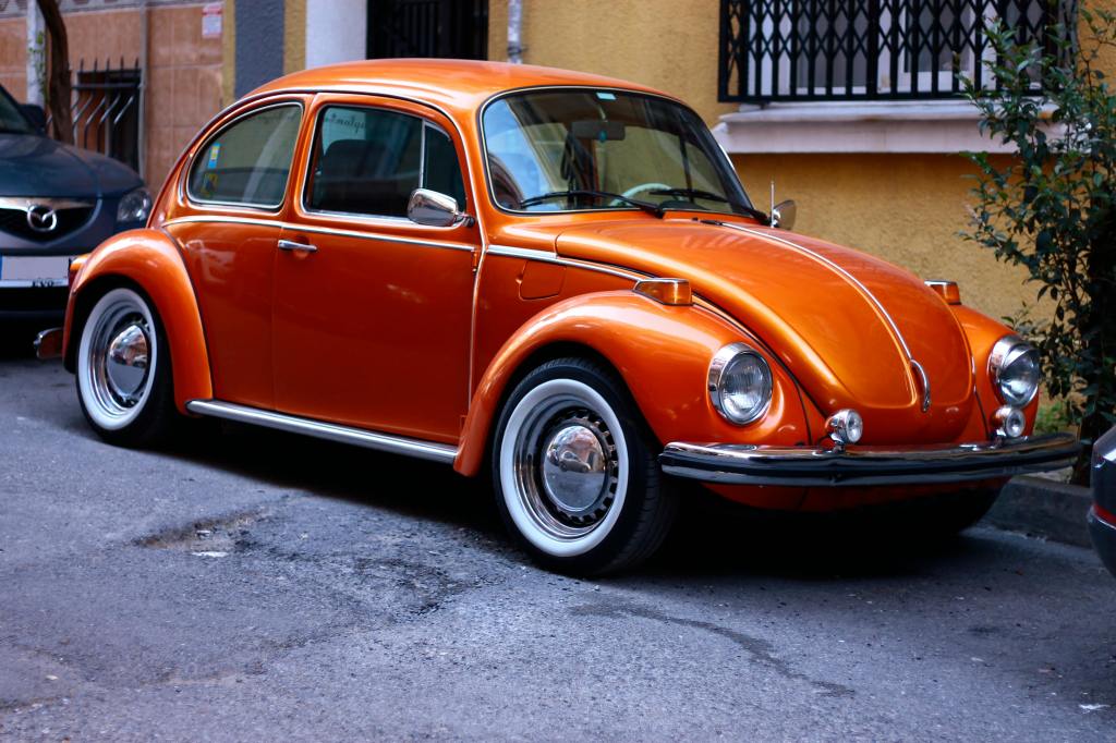 Orange color Volkswagen Beetle parked in front of a building